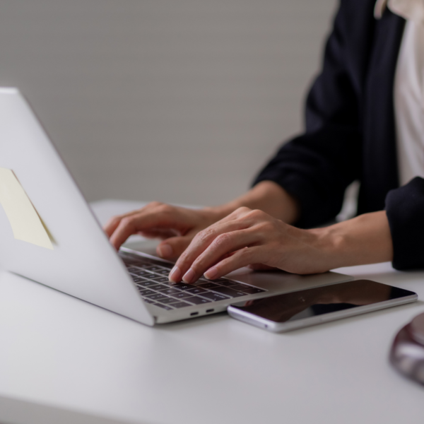 Professional using a laptop at a desk with a mobile phone nearby